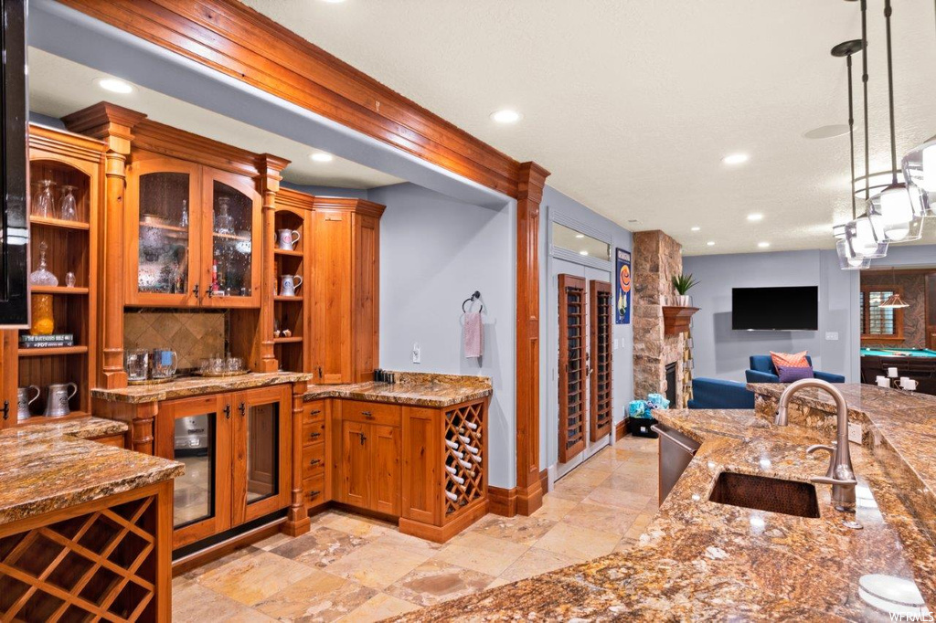 Kitchen with light granite-like countertops, light tile floors, backsplash, and brown cabinets