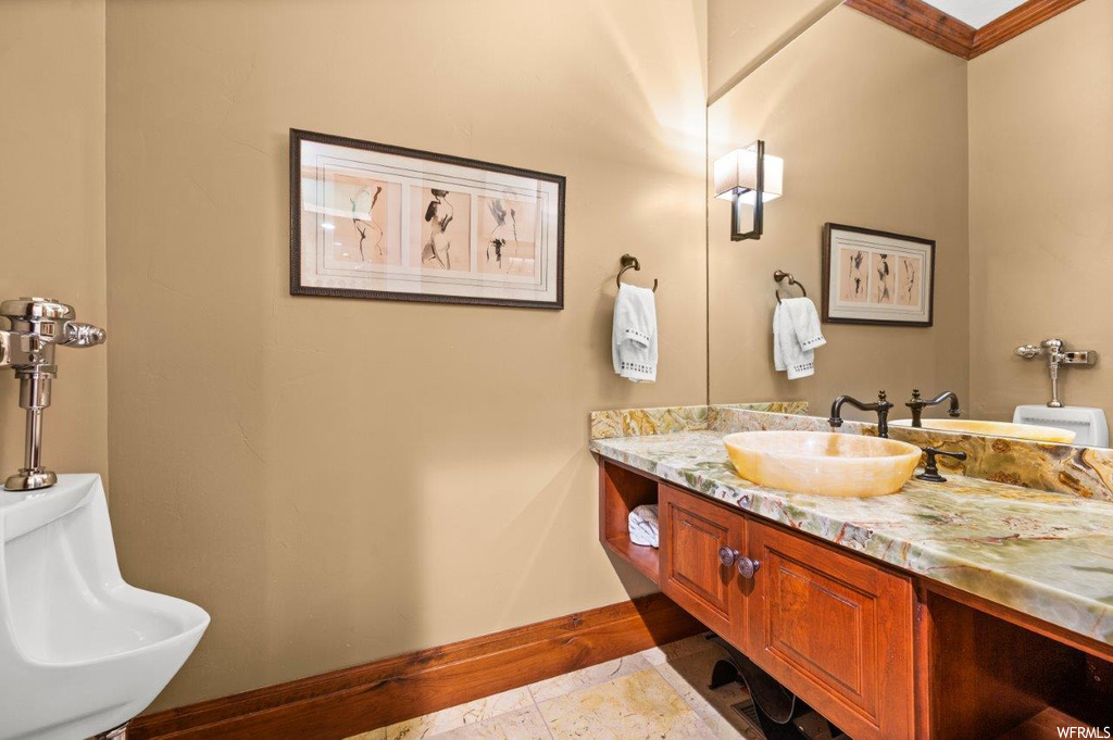 Bathroom with ornamental molding, sink, tile flooring, and mirror