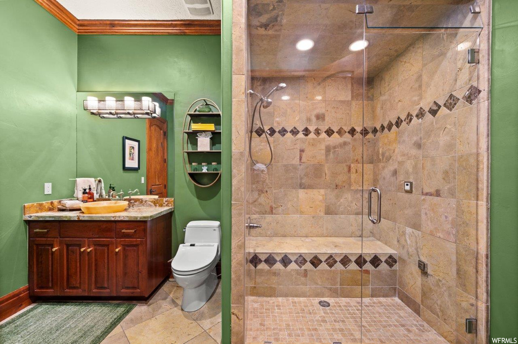 Bathroom with ornamental molding, light tile flooring, mirror, oversized vanity, and an enclosed shower