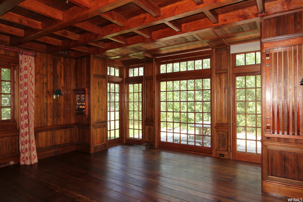 Wood floored empty room with wood walls, coffered ceiling, beam ceiling, and wooden ceiling