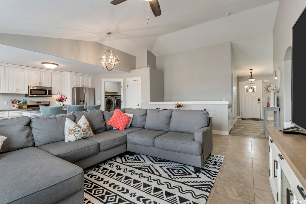 Tiled living room featuring a high ceiling, washer / clothes dryer, lofted ceiling, and ceiling fan
