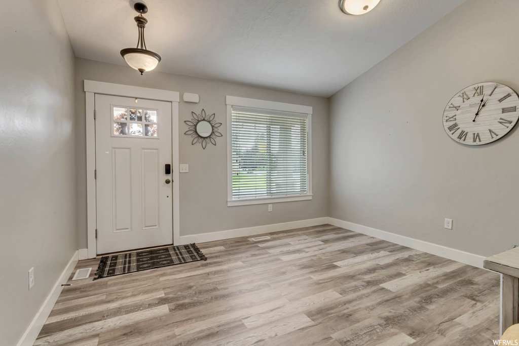 Entryway with light hardwood floors and lofted ceiling