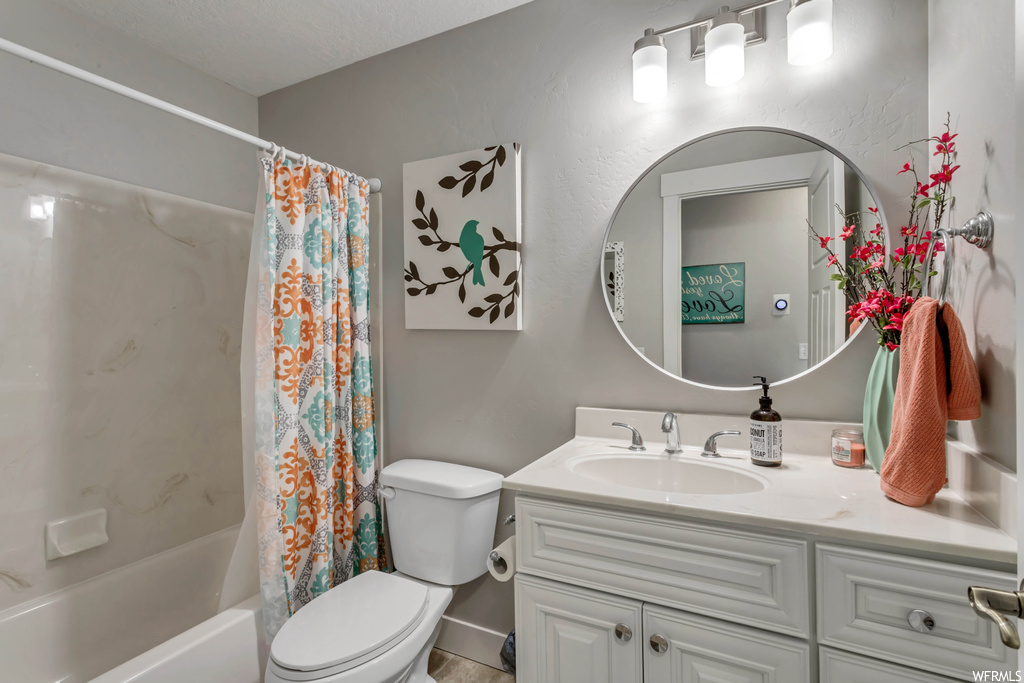Full bathroom with shower / bath combo with shower curtain, large vanity, a textured ceiling, and mirror