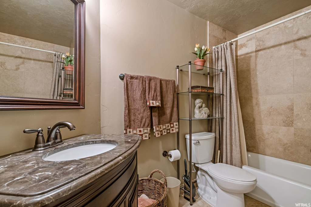 Full bathroom with shower / bathtub combination with curtain, vanity, a textured ceiling, and mirror
