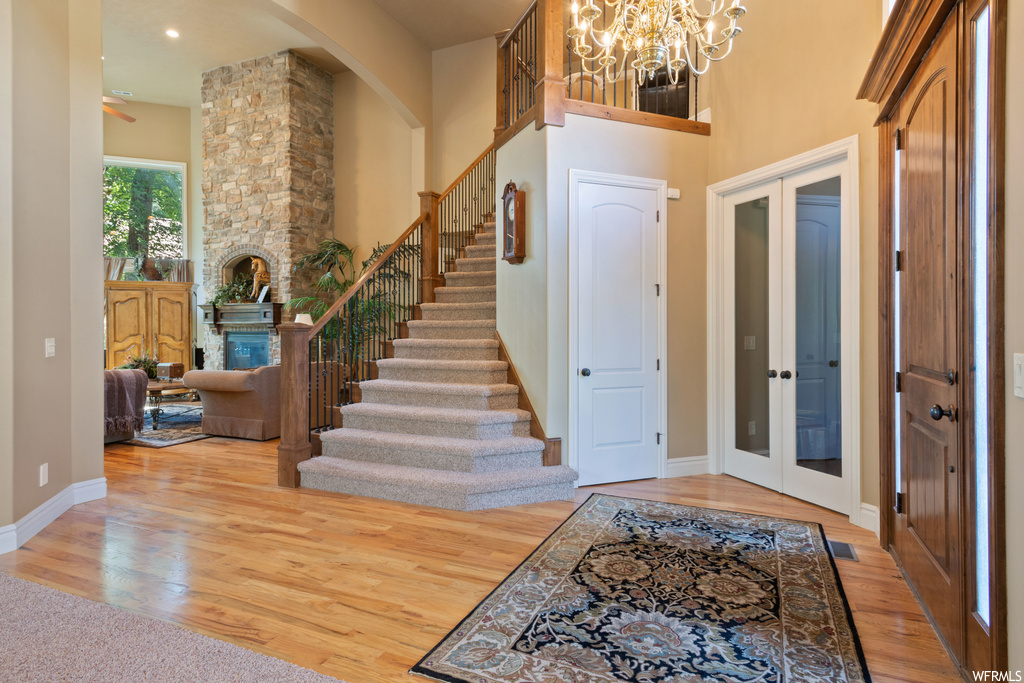 Entrance foyer with a notable chandelier, light hardwood floors, and a high ceiling