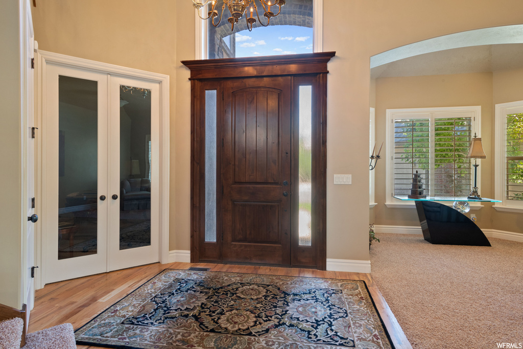 Carpeted foyer entrance featuring a notable chandelier and french doors