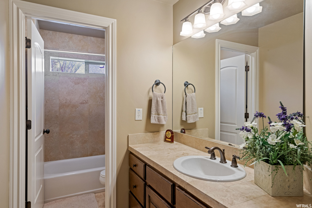Full bathroom featuring light tile floors, vanity, tiled shower / bath, and mirror