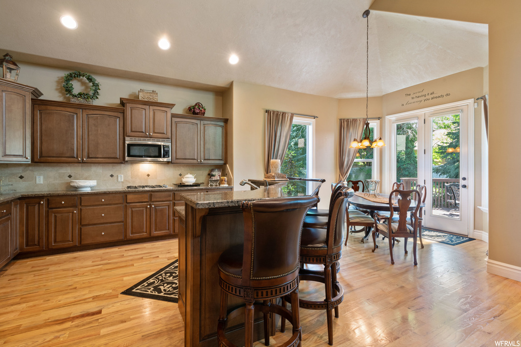 Kitchen with backsplash, stone counters, and light hardwood flooring