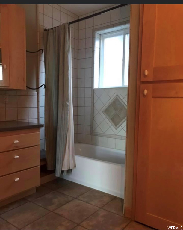 Bathroom featuring shower / tub combo with curtain and tile flooring