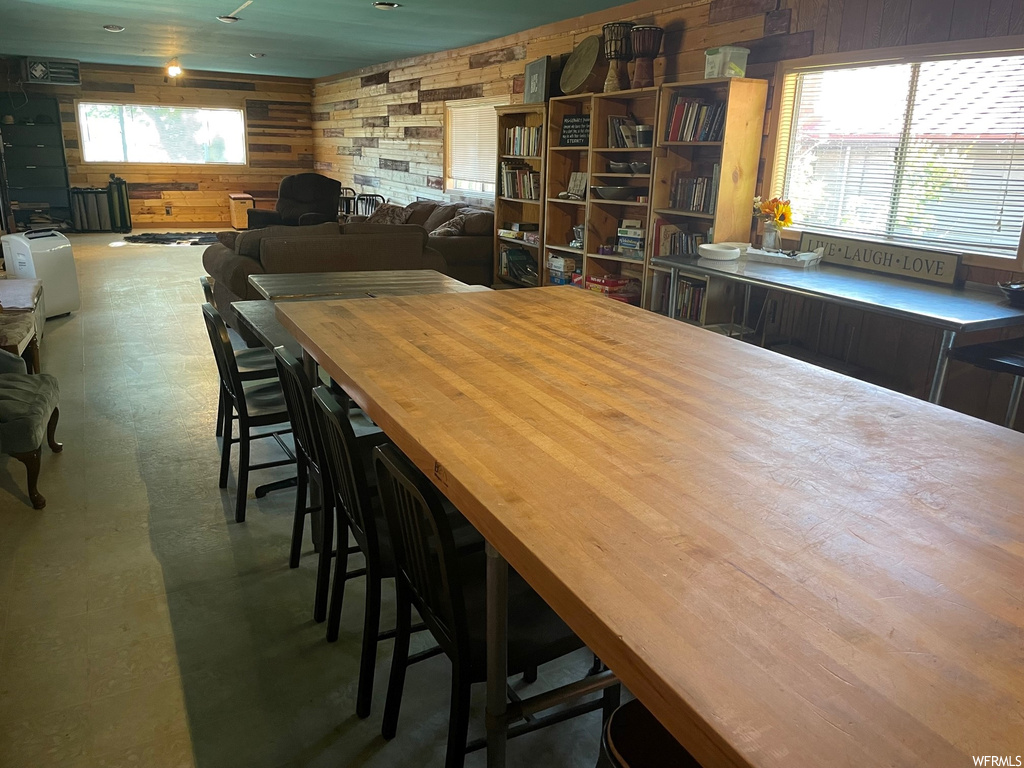 Dining area featuring wood walls, plenty of natural light, and dark hardwood floors