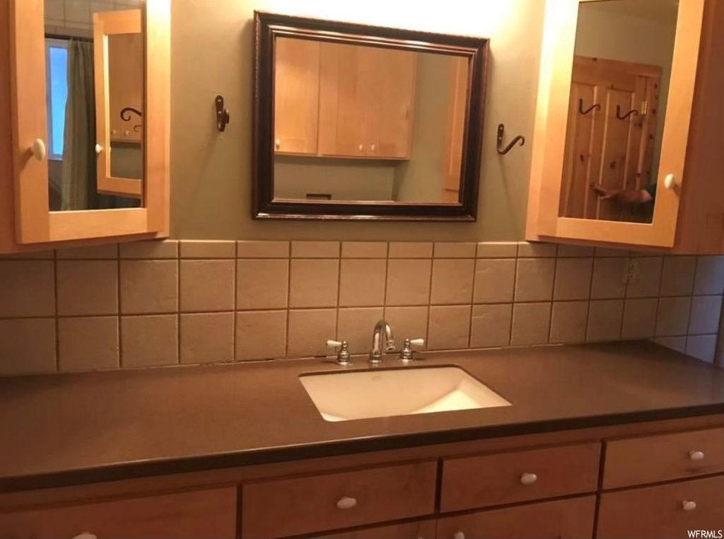 Bathroom featuring vanity, backsplash, and mirror
