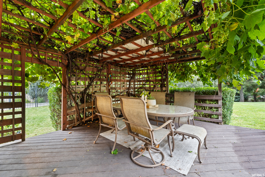 Wooden deck featuring a pergola and a lawn