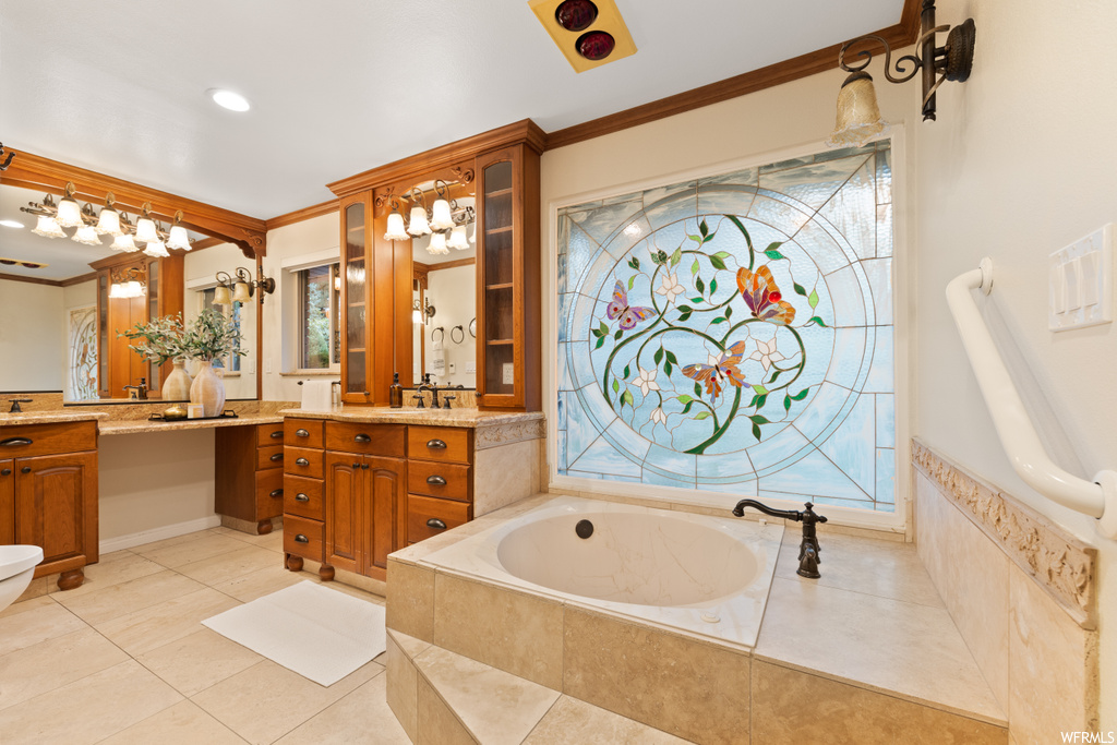 Bathroom featuring ornamental molding, mirror, light tile floors, large vanity, and a relaxing tiled bath