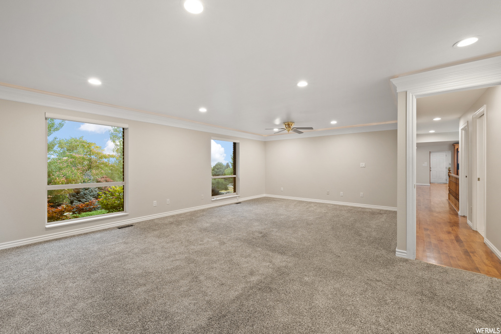 Wood floored spare room with crown molding, plenty of natural light, and ceiling fan