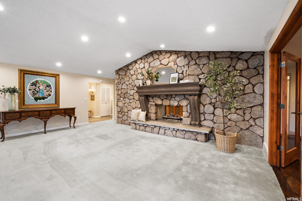 Carpeted living room featuring a fireplace and lofted ceiling