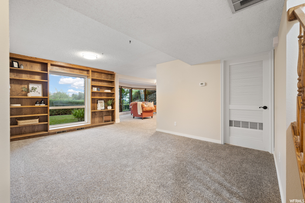 Carpeted living room featuring plenty of natural light and a textured ceiling