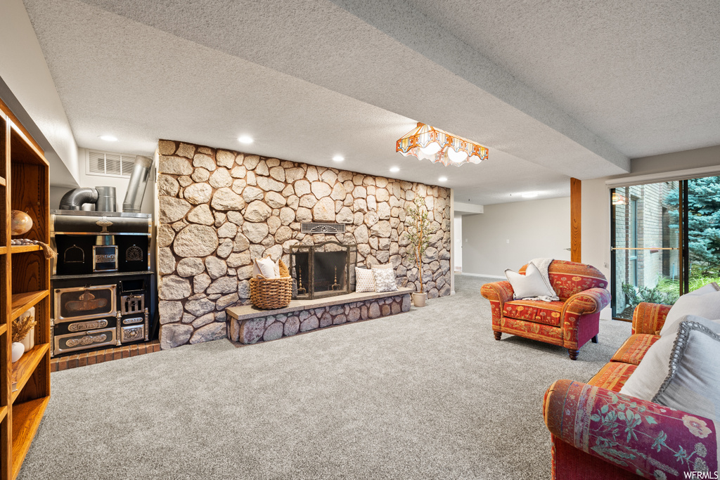 Living room featuring a textured ceiling, a fireplace, and carpet flooring