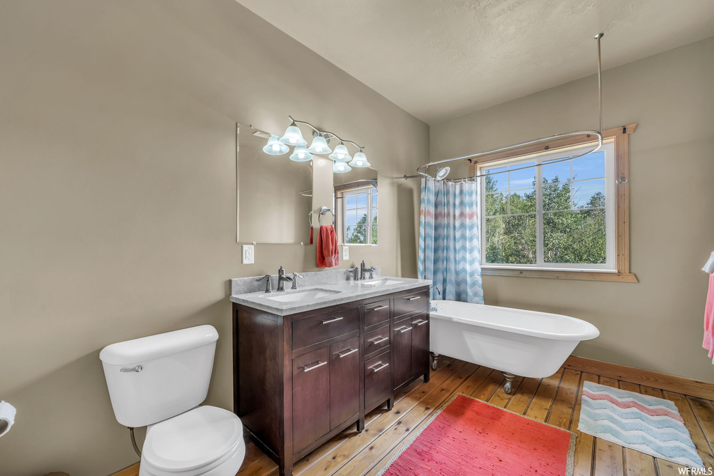 Bathroom with double sink vanity, mirror, and light hardwood floors