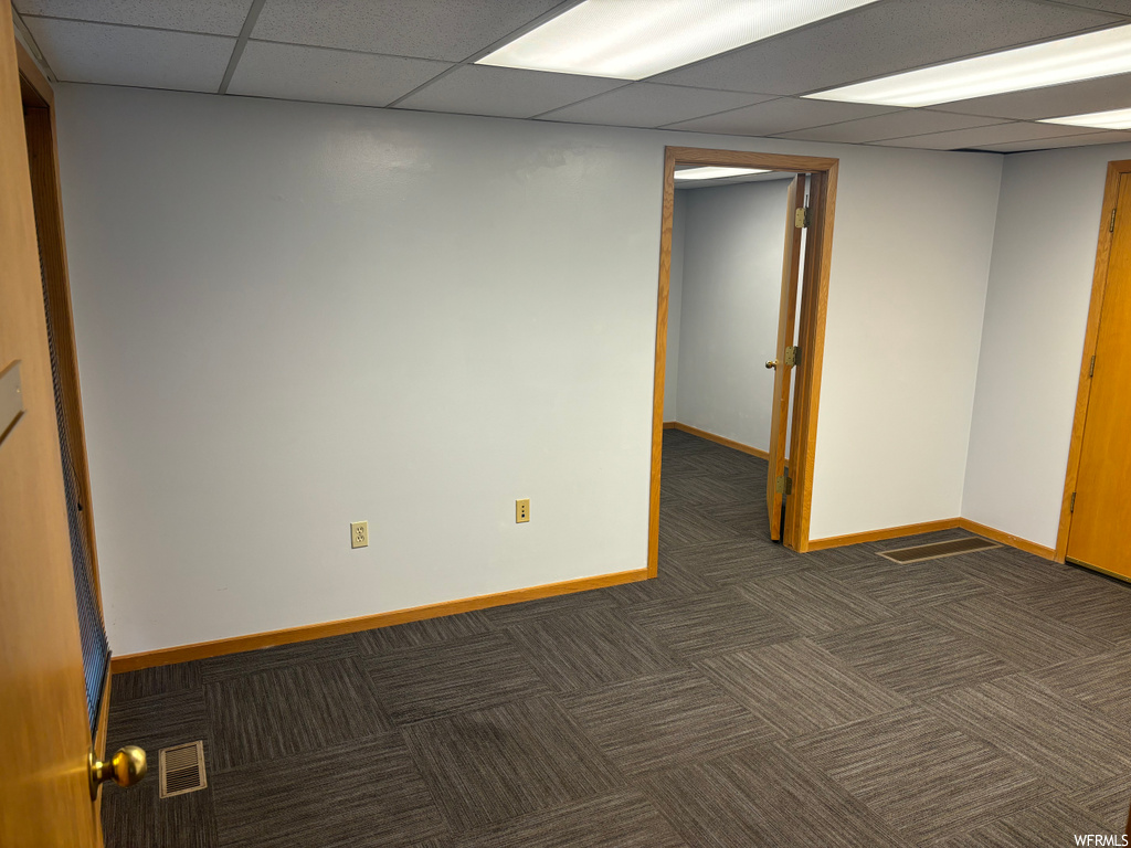 Unfurnished room with dark carpet and a paneled ceiling