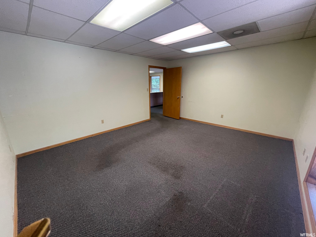 Carpeted spare room featuring a drop ceiling