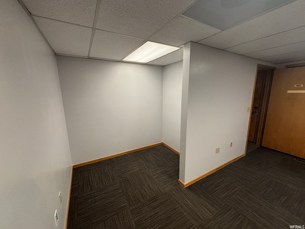 Basement with dark carpet and a drop ceiling