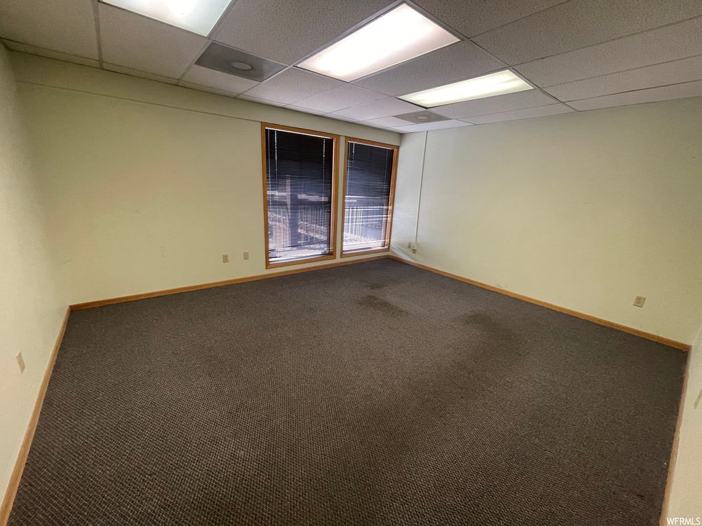 Carpeted empty room featuring a drop ceiling