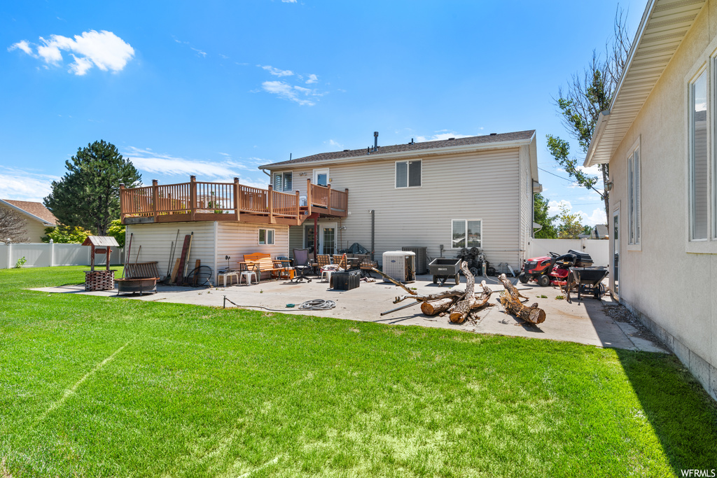 Back of property with a yard, a patio, and wooden deck