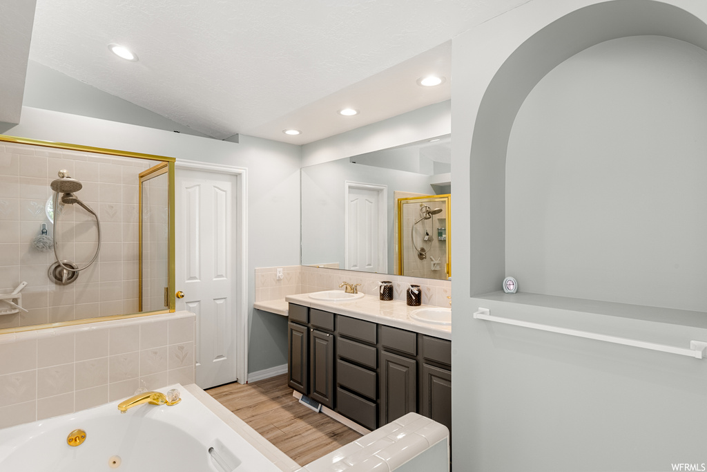 Bathroom featuring dual large vanity, separate shower and tub, mirror, and light hardwood floors