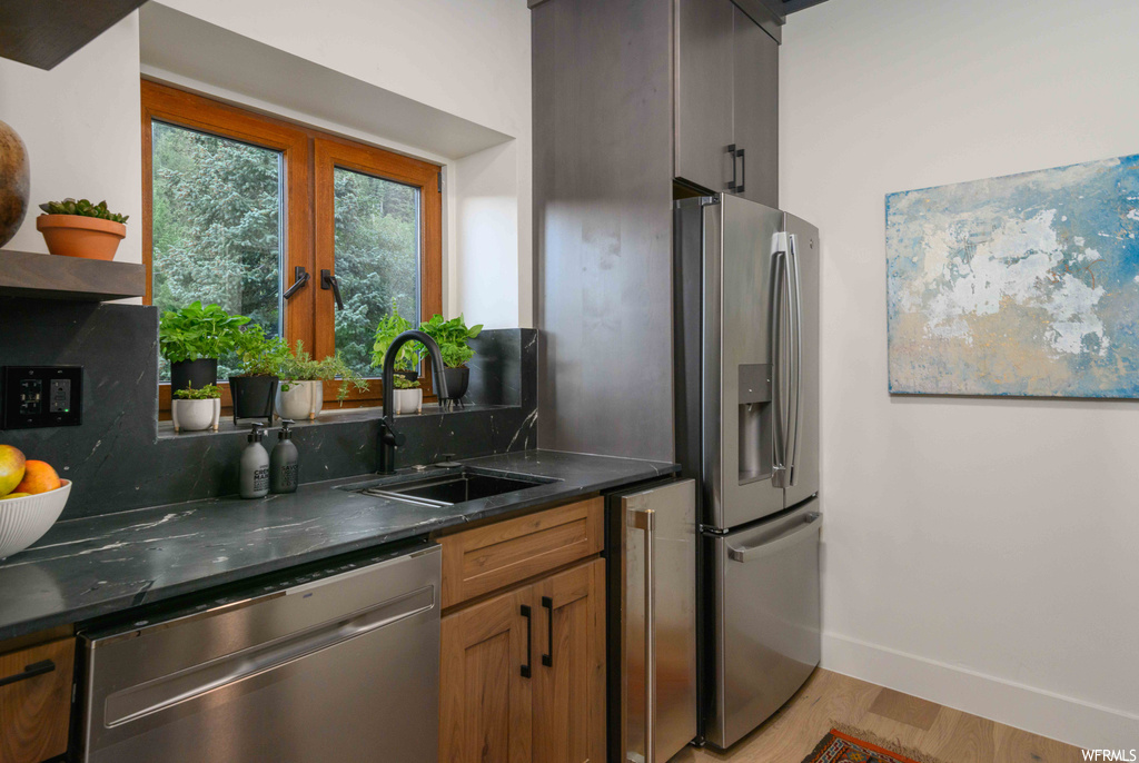Kitchen with dark countertops, appliances with stainless steel finishes, french doors, and light hardwood flooring