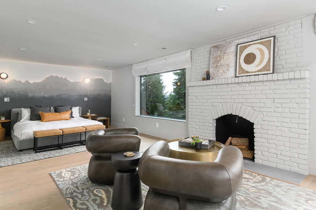 Living room featuring brick wall, a fireplace, and light hardwood flooring