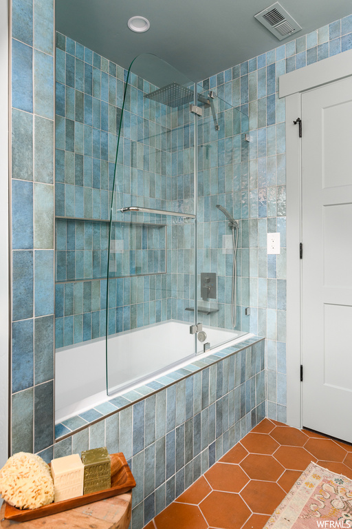 Bathroom featuring tiled shower / bath, light tile floors, and tile walls