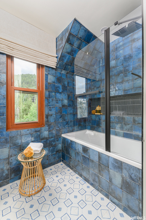 Bathroom with shower with separate bathtub, light tile floors, and tile walls