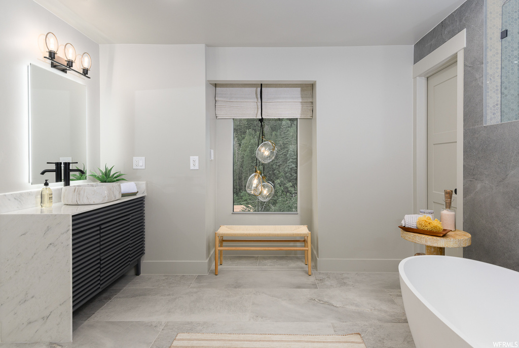 Bathroom featuring light tile flooring, vanity, a bath, and mirror