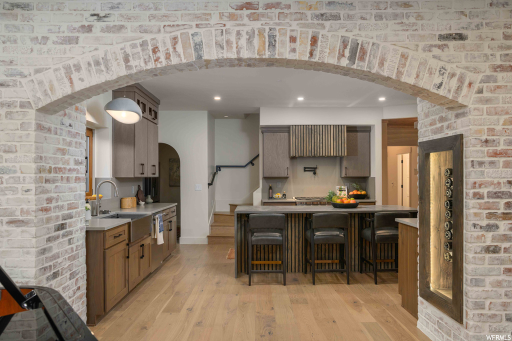 Kitchen with a center island, brick wall, light hardwood flooring, and light countertops