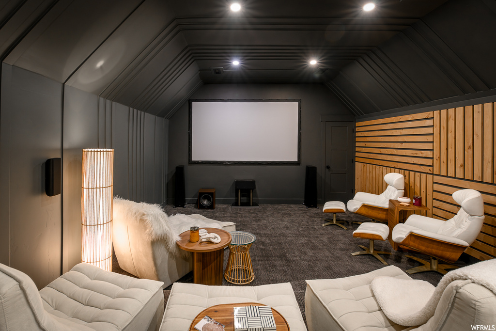 Home theater featuring lofted ceiling, wooden walls, and carpet flooring