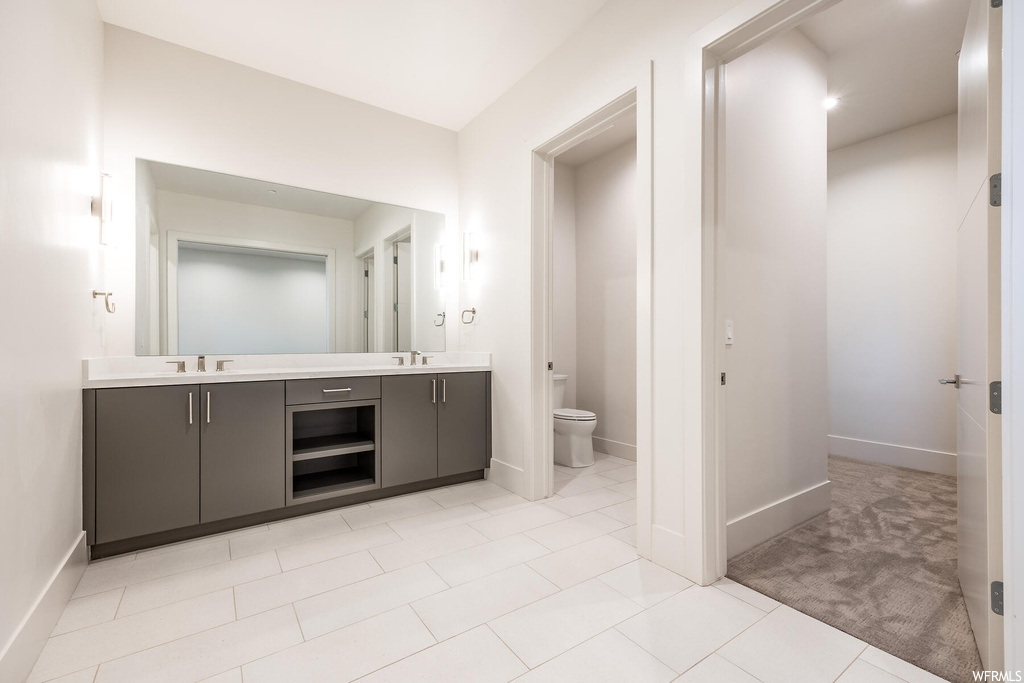 Bathroom featuring vanity with extensive cabinet space, light tile flooring, and mirror