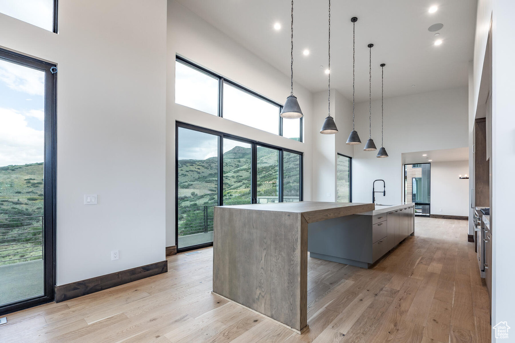 Kitchen with a spacious island, a high ceiling, light hardwood / wood-style flooring, and hanging light fixtures