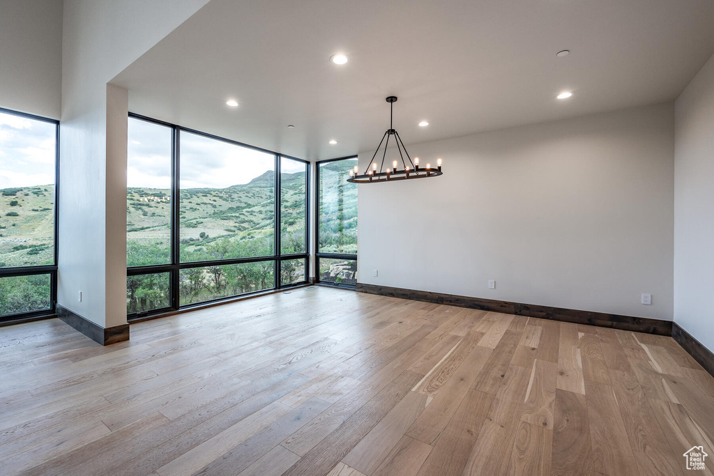 Unfurnished room featuring floor to ceiling windows, a chandelier, and light hardwood / wood-style floors