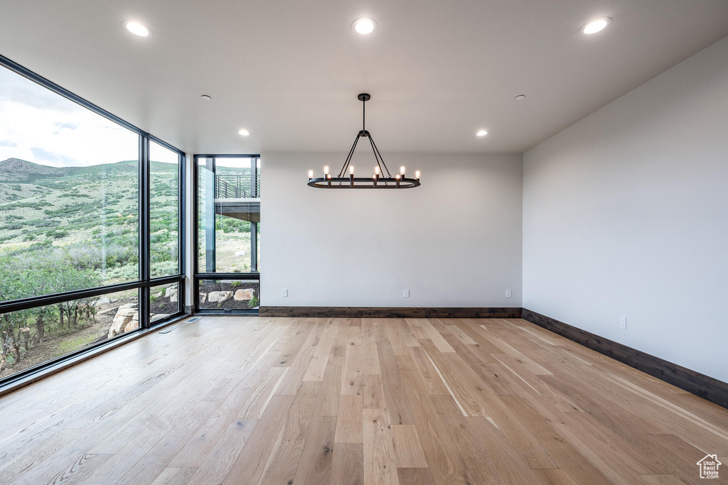 Interior space featuring plenty of natural light, floor to ceiling windows, an inviting chandelier, and light hardwood / wood-style floors