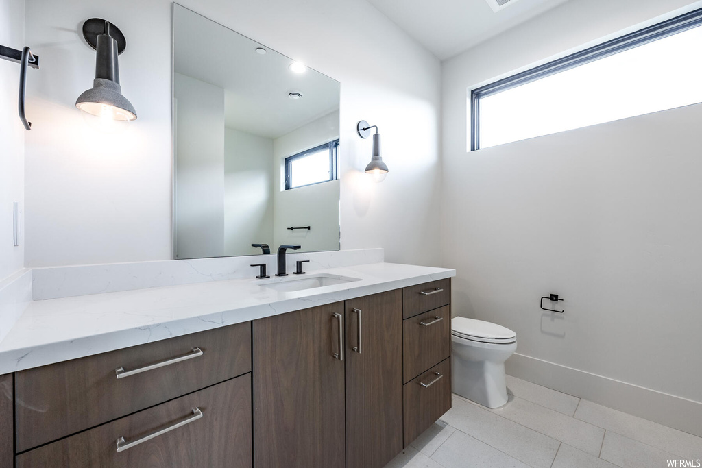 Bathroom featuring a wealth of natural light, vanity, mirror, and light tile floors