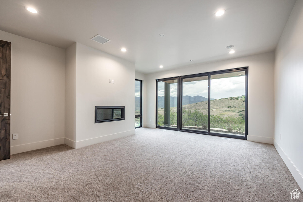 Unfurnished living room featuring a mountain view and light carpet