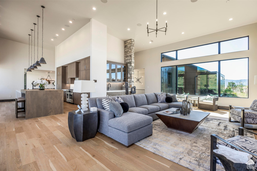 Living room with light hardwood / wood-style flooring, a towering ceiling, and a chandelier