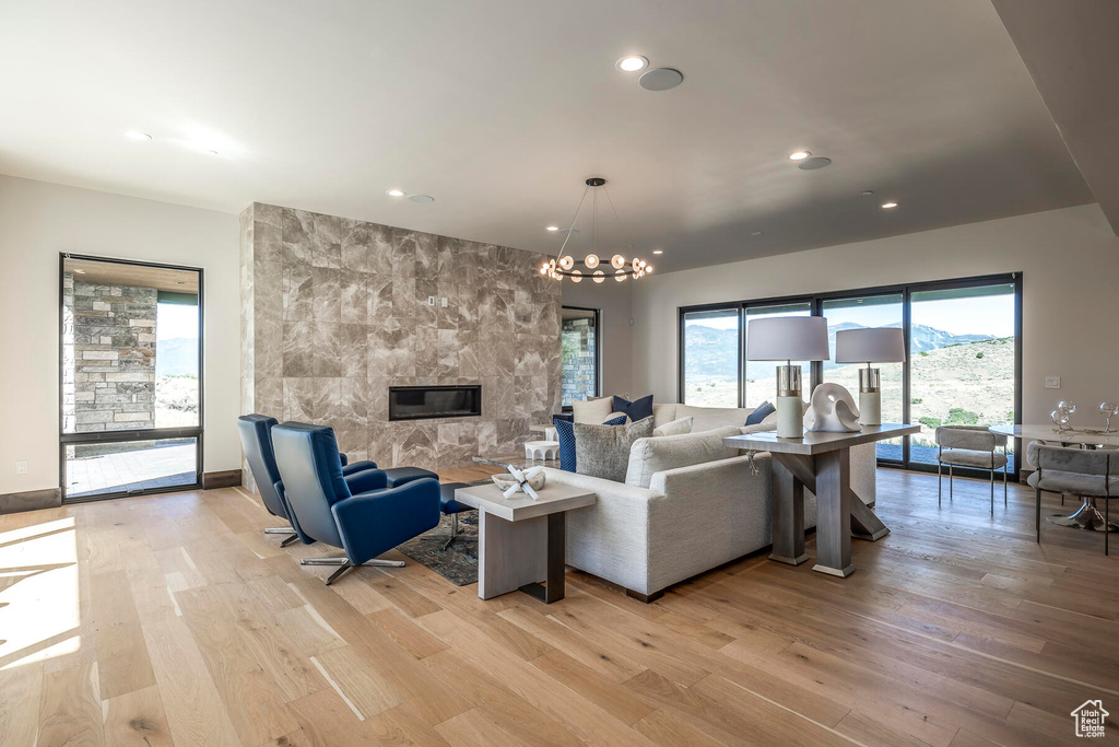 Living room with a chandelier, a fireplace, and light hardwood / wood-style floors