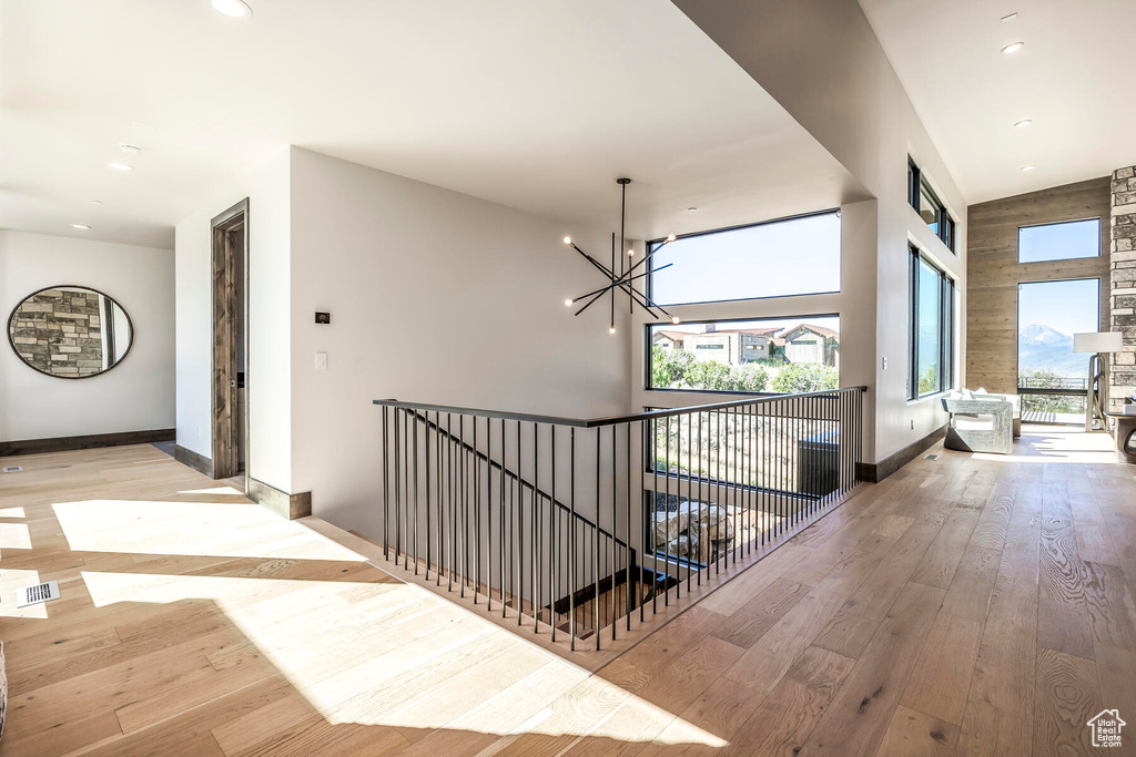 Corridor with vaulted ceiling, a chandelier, and light hardwood / wood-style flooring