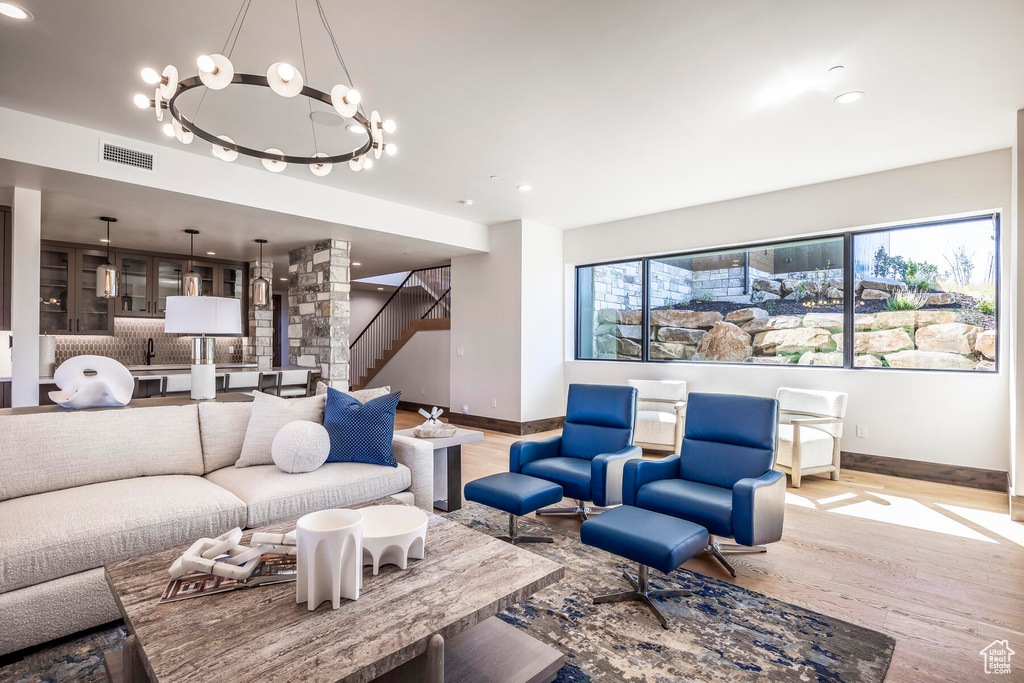 Living room with an inviting chandelier, sink, and light hardwood / wood-style floors