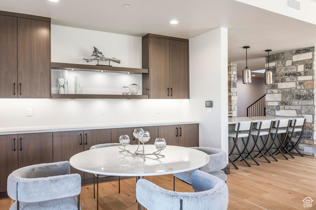 Kitchen featuring dark brown cabinets, light hardwood / wood-style flooring, and hanging light fixtures