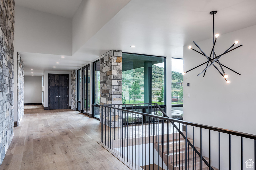 Hall with light wood-type flooring, a chandelier, and floor to ceiling windows