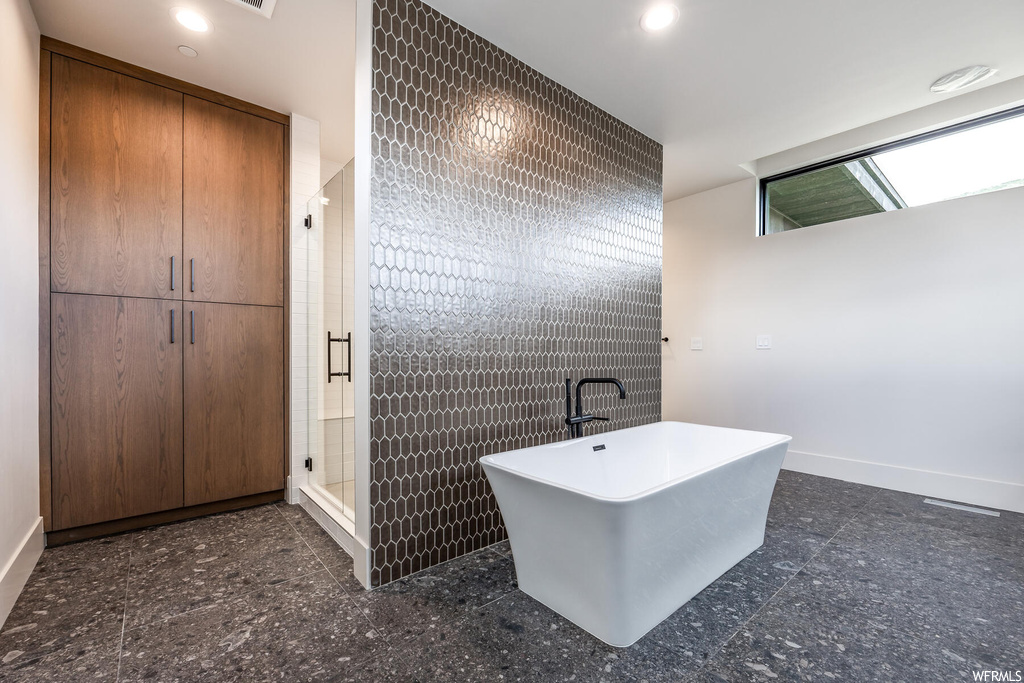Bathroom featuring separate shower and tub enclosures, tile flooring, and tile walls