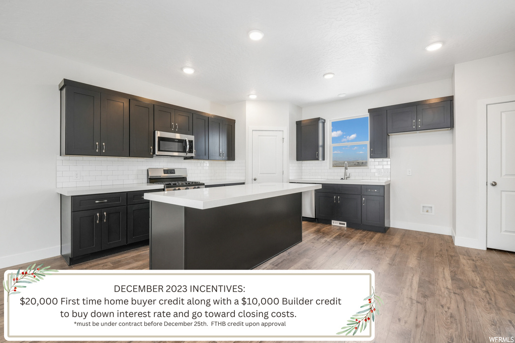 Kitchen with a kitchen island, tasteful backsplash, stainless steel appliances, and hardwood / wood-style floors