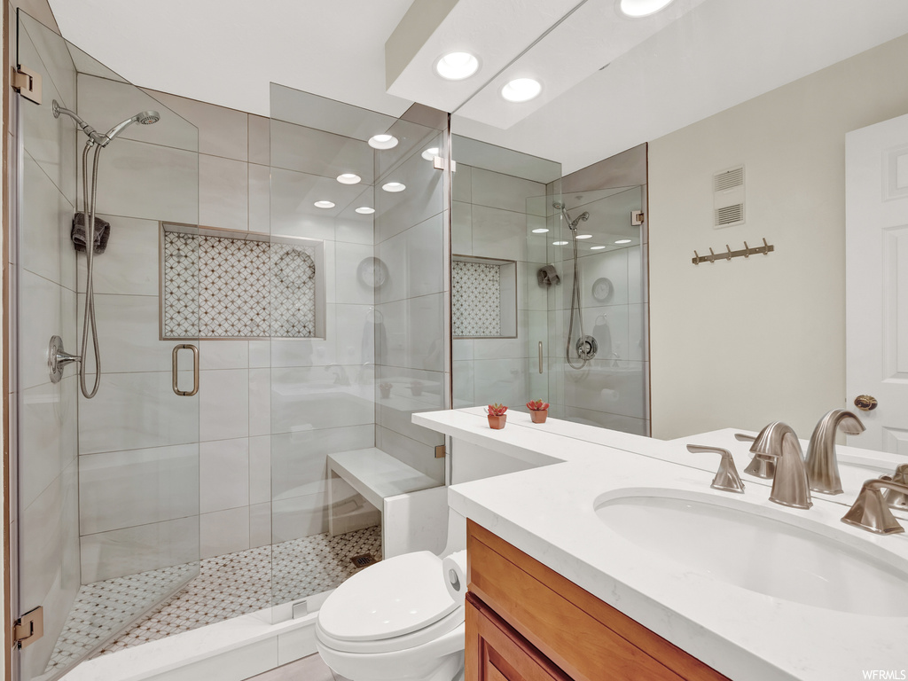 Bathroom with a shower with shower door, mirror, and vanity with extensive cabinet space